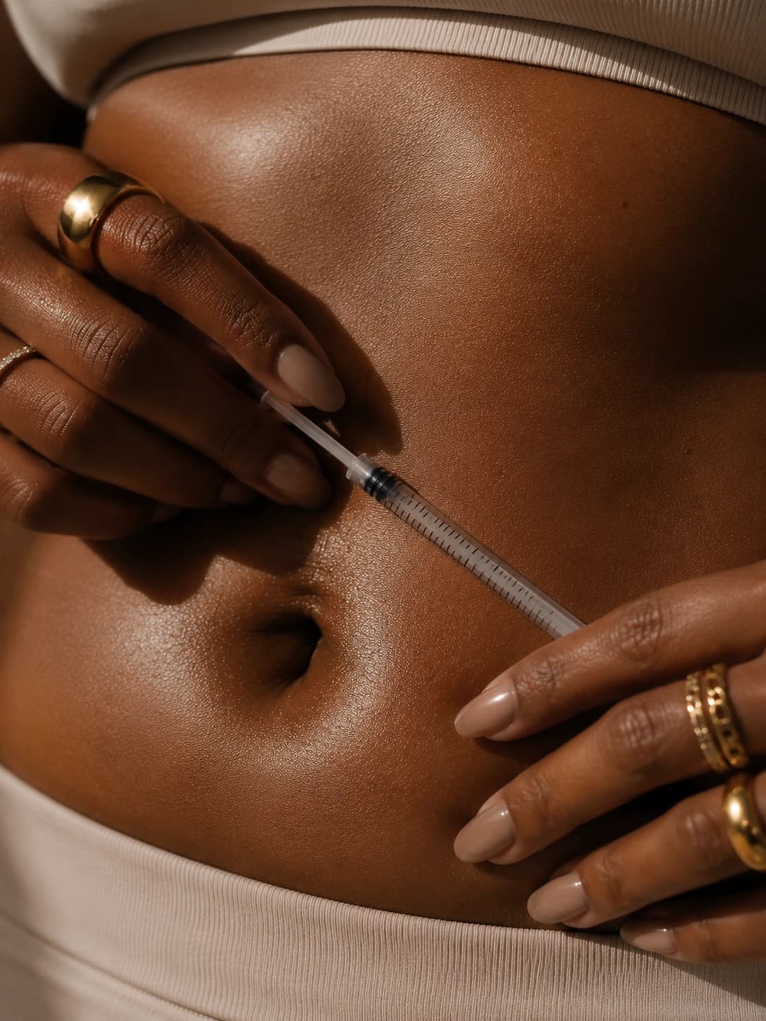 A woman administering her Atelier Protocol protocol at home, styled with fine gold jewelry